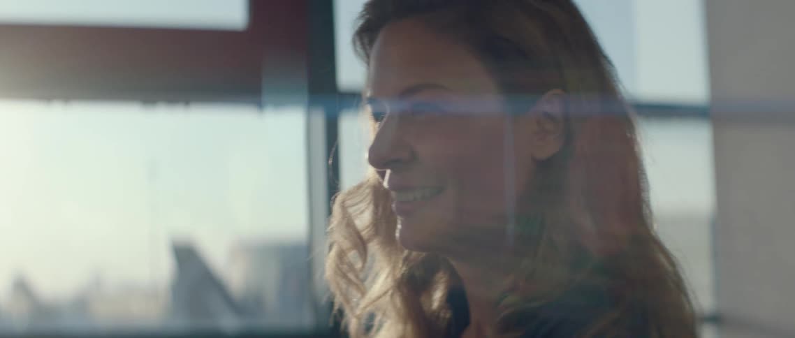 A woman stands in front of a window at an airport laughing