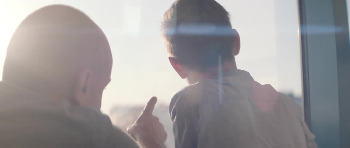 A father points out the window as he talks to his son