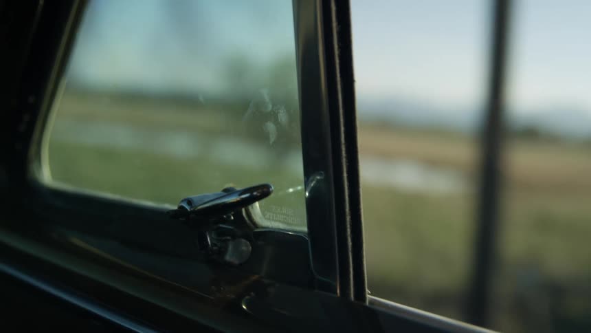 A vehicle drives past the green fields