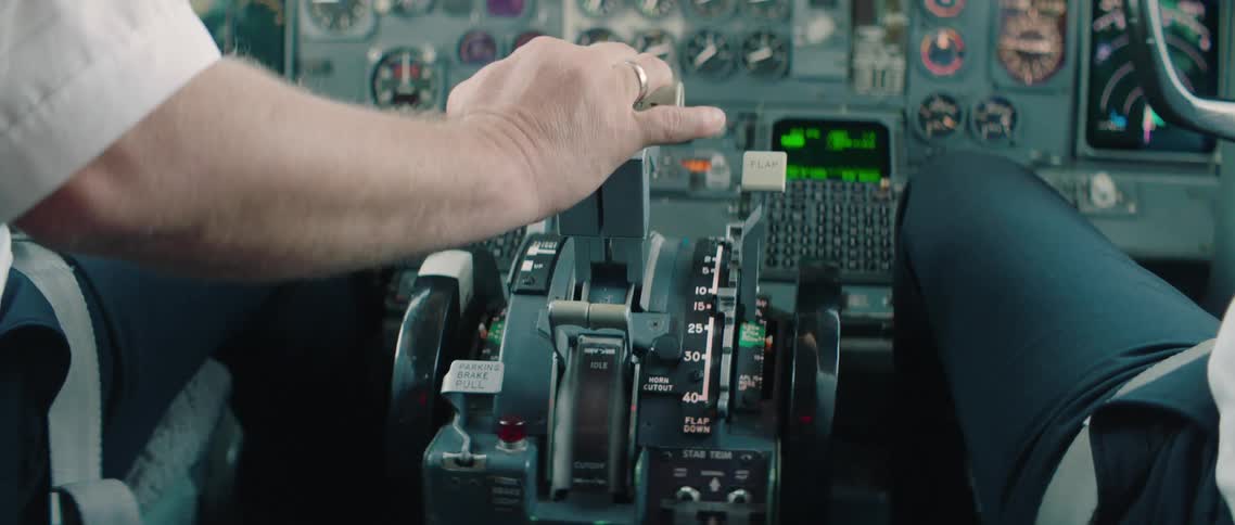 A white man has his hand on the throttle of an aircraft