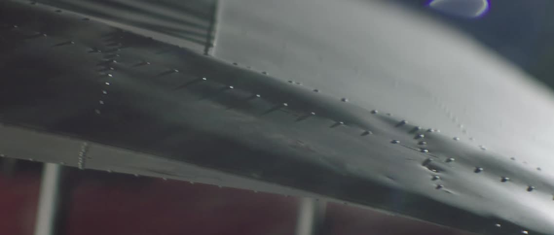 Close up of an airplane wing inside a dimly lit hangar