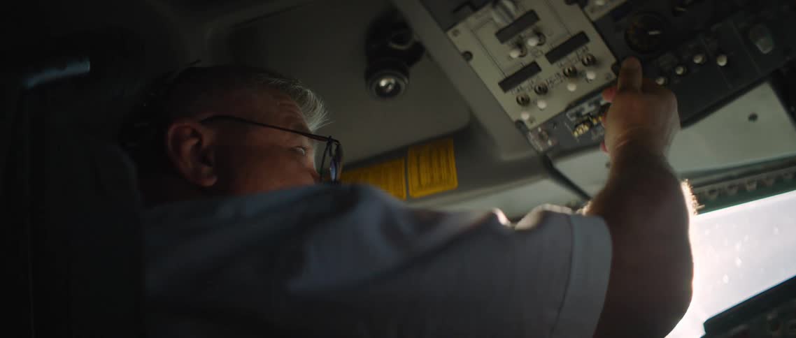 A pilot in a cockpit touching buttons