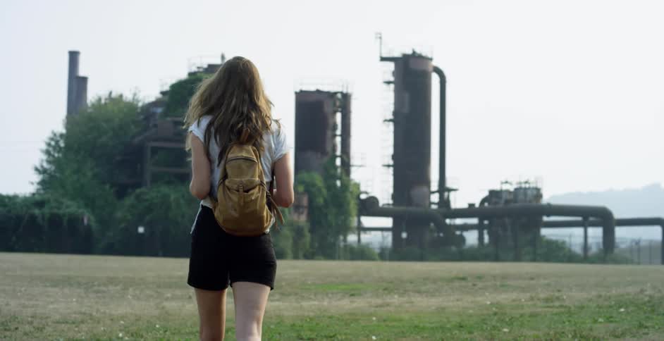 A woman walks towards the building by the plant