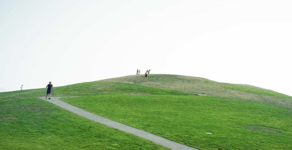 Man walks along path away from hill