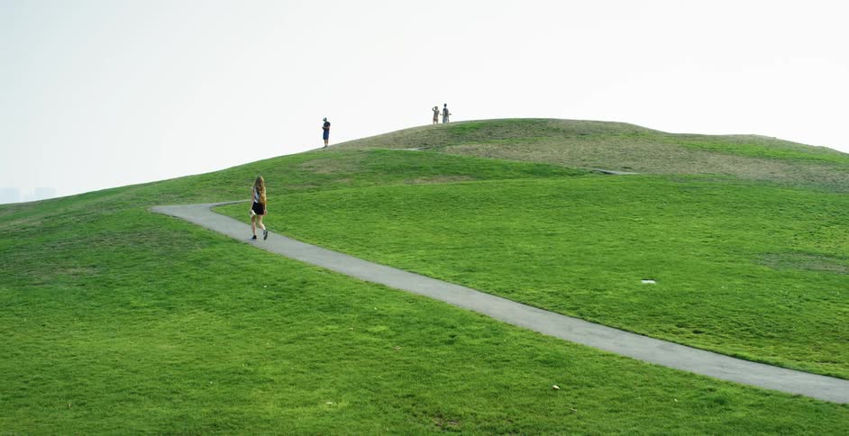 Female walking up a pathway on grassy hill outdoors