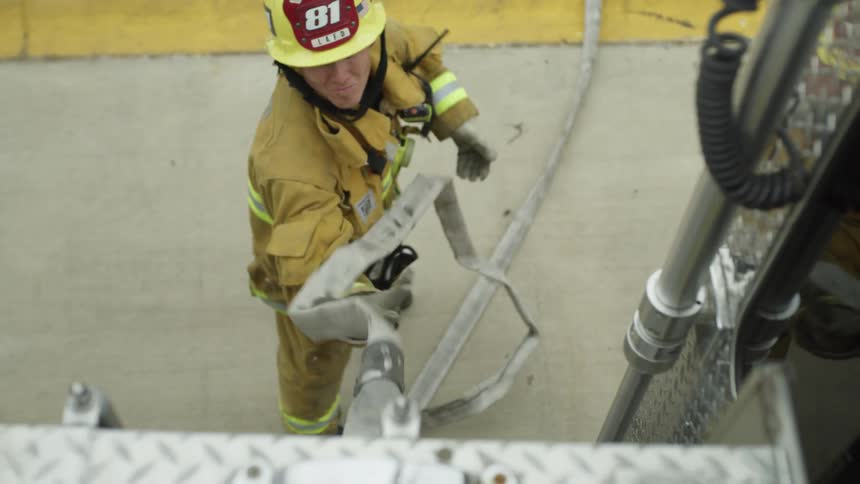 A firefighter pulls a hose down
