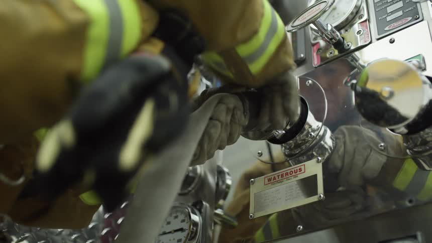 A firefighter screws a hose on to a spout
