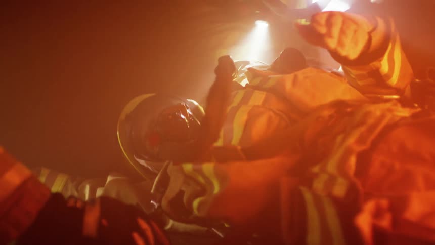 Two firefighters help a firefighter on the ground