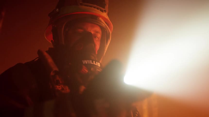 A firefighter shines his flashlight while searching a room