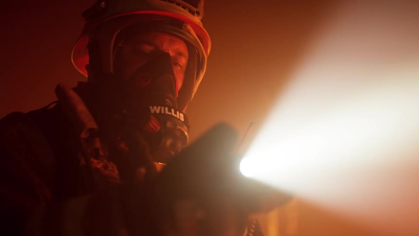 A firefighter with a flashlight a mask and a helmet