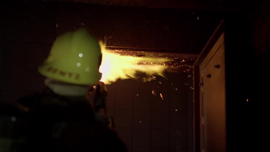A firefighter uses a torch inside a building