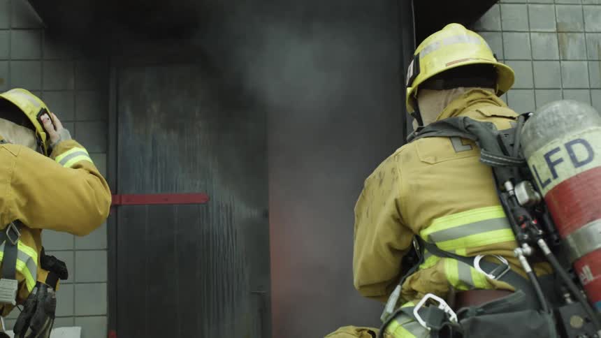 Firefighters get ready to enter a building in flames in a training exercise