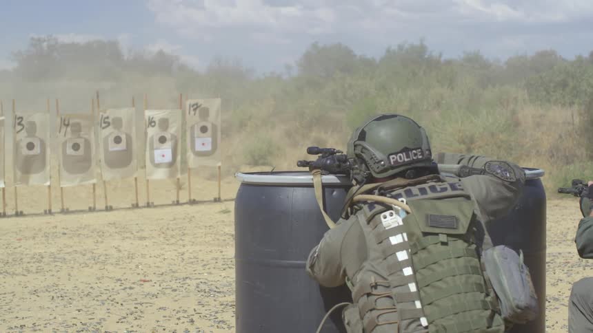 Police officers in military uniform shoot assault weapons at practice targets