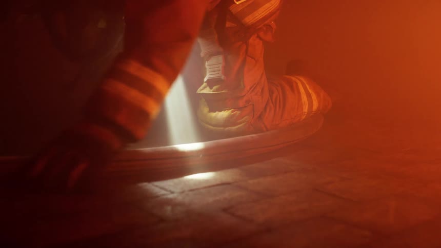 Two firefighters crawl through the smoke while holding flashlights