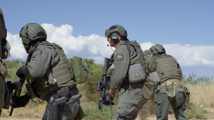 Military police are training on an outdoor firing range as they turn around and take aim at targets