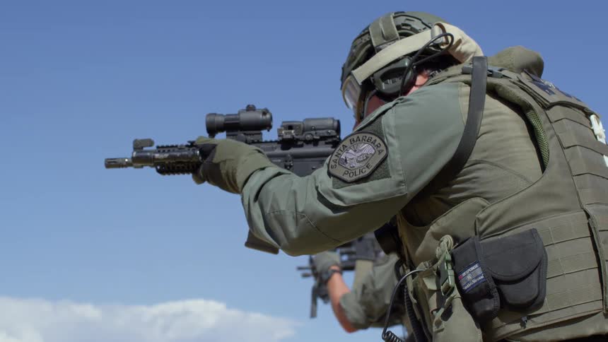 Two police aim their guns and fire