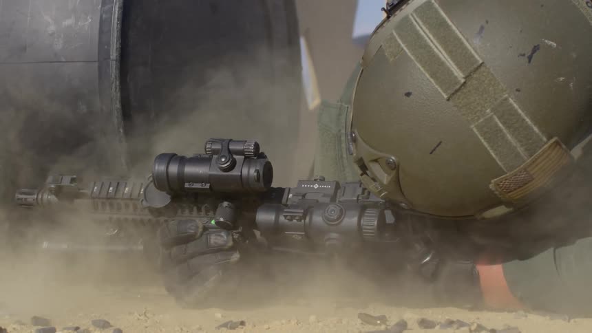 A soldier lies on the ground and shoots a gun