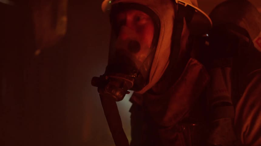 Two firefighters walk through a smoke filled building