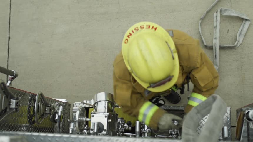 Fireman adjusting water hose to side of fire truck