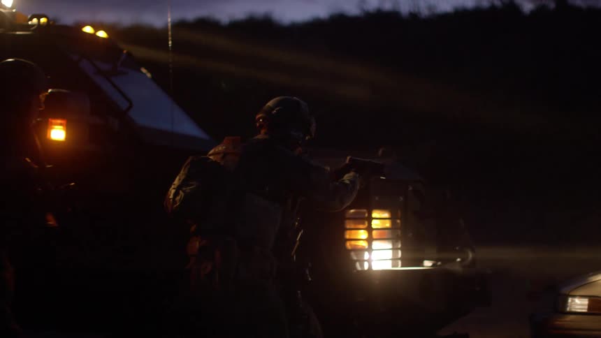 Soldiers fire into a car as they retreat behind a military vehicle
