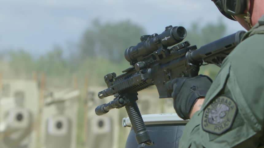 A police officer practices shooting at targets lined up in a field