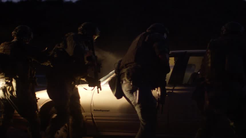 Soldiers open the door to the vehicle pointing guns