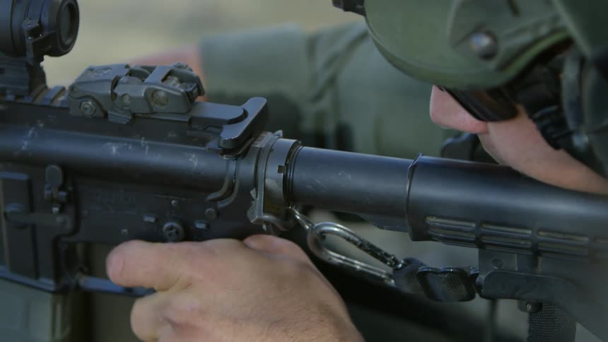 A soldier is firing a rifle on an outdoor firing range