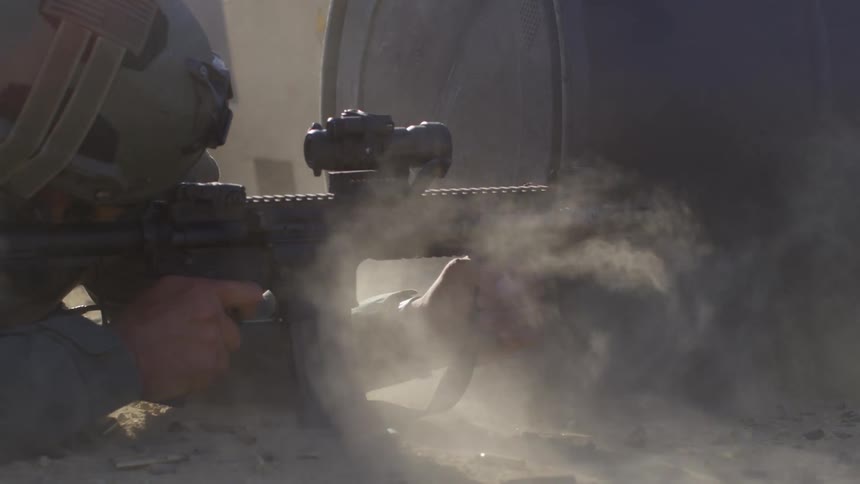 A soldier on the ground fires his rifle