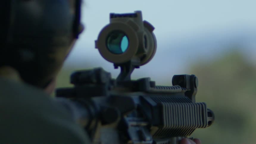 A person with a uniform and helmet shooting a rifle