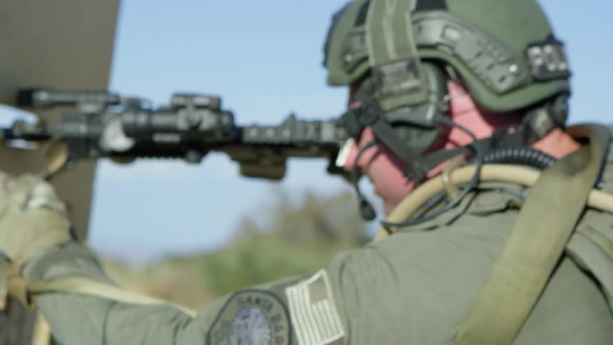 Police officer in full combat gear fires a tactical assault rifle