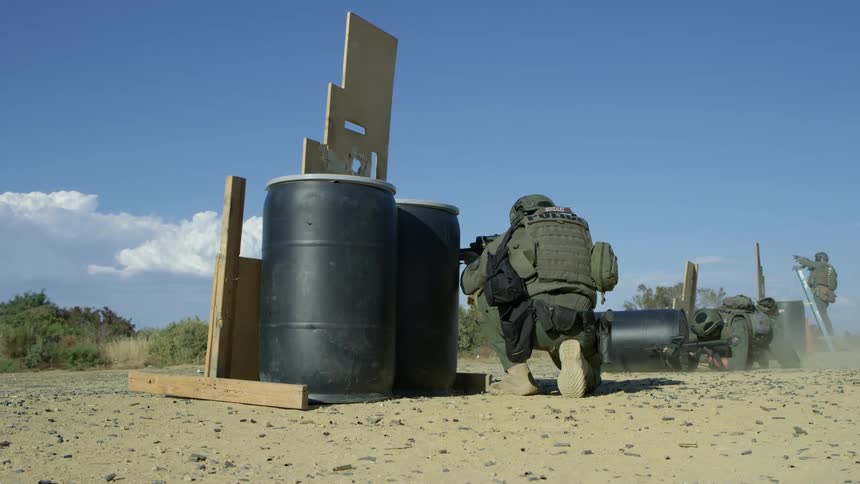 Three soldiers shoot guns at a shooting range