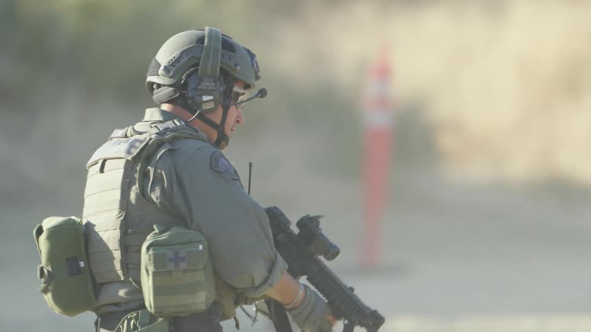 A soldier runs and takes cover behind a car and then aims his gun