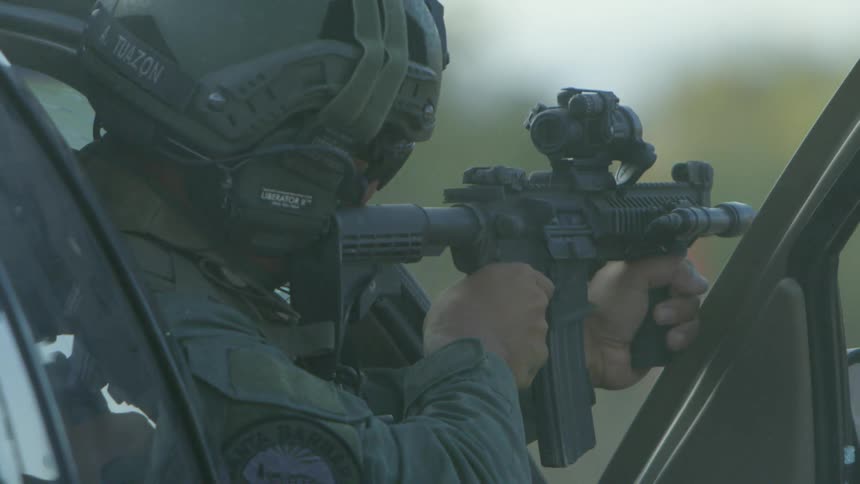 Bullet casings eject from a rifle being fired by a police officer in tactical gear