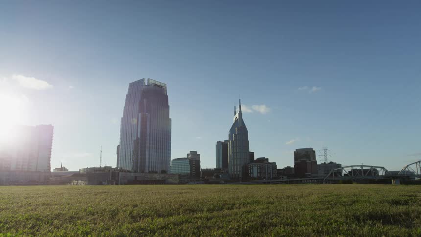 Downtown city skyline under a blue sky in front of a field of green grass