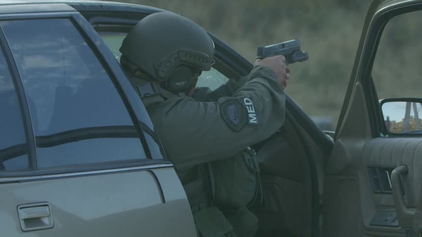 A man is firing his gun from the car
