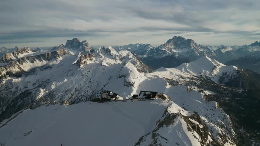 Buildings occupy mountain snow covered mountain ridge under overcast sky
