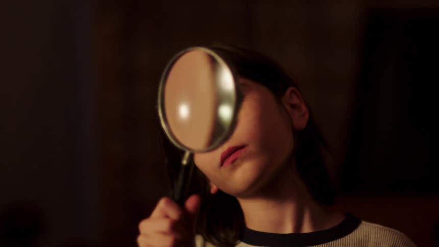 A boy turns a magnifying glass back and forth as he looks through