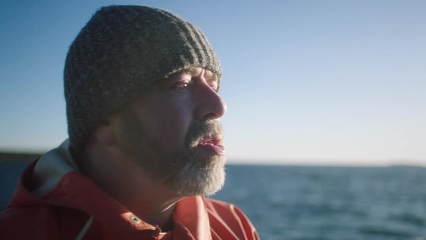 A man working on a vessel in the ocean stops to drink water from a bottle