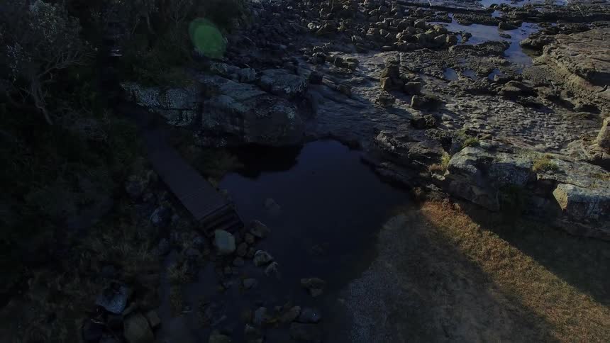 Slowly moving above a rocky coastline on a sunny day