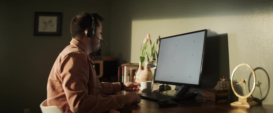 A white man drinks from a mug while sitting at his computer