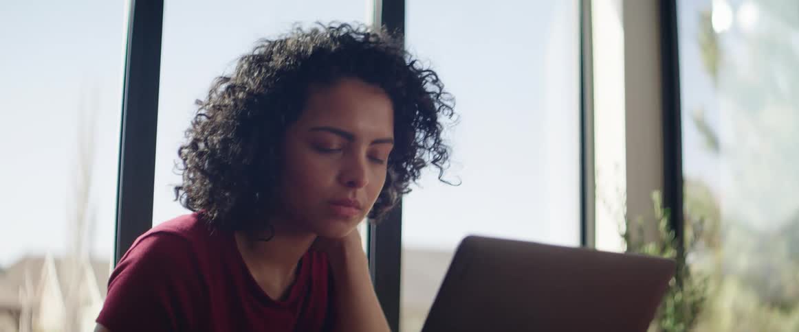 A teenager sits inside and uses her laptop