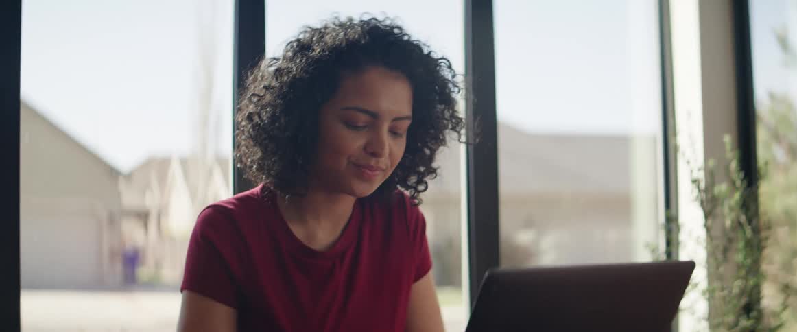 Young woman sits down at table and opens laptop