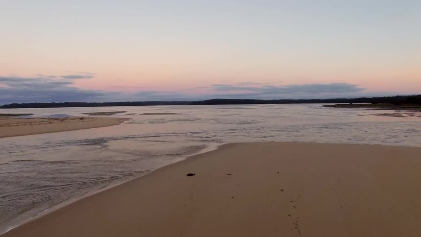 Ocean waters overtaking a large beach at dusk