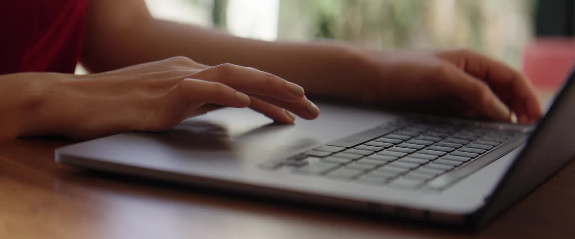Hands typing on laptop keyboard