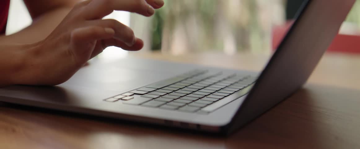 A persons hands typing on a laptop