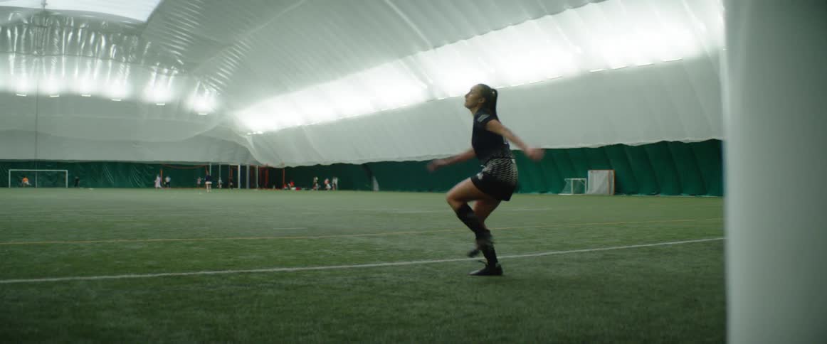 A soccer player practices kicking a ball into the net in an indoor field