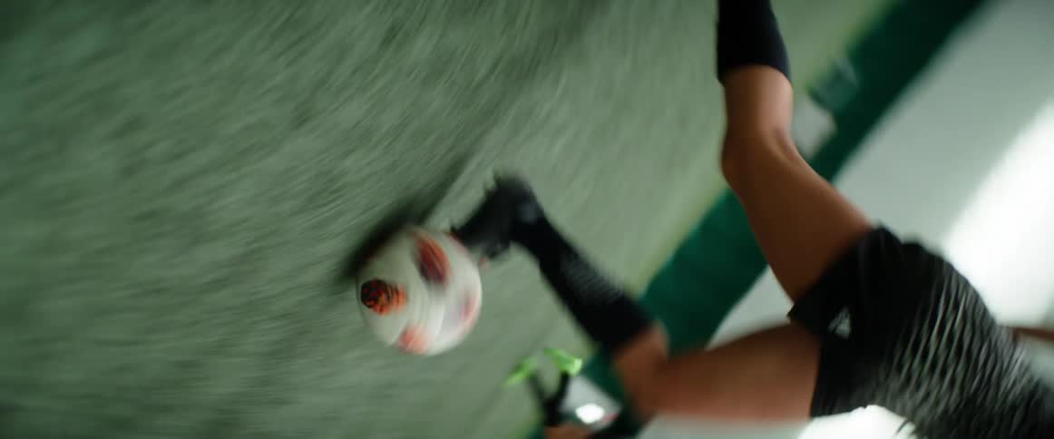 Chaotic filming of soccer player dribbling ball across indoor soccer field