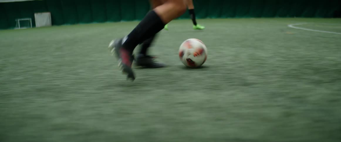 Legs of soccer player dribbling ball down the field