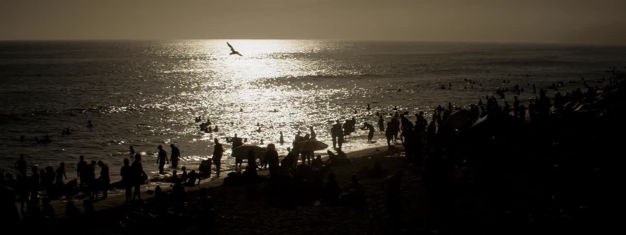 A large crowd gathered at a beach for hanging out and swimming