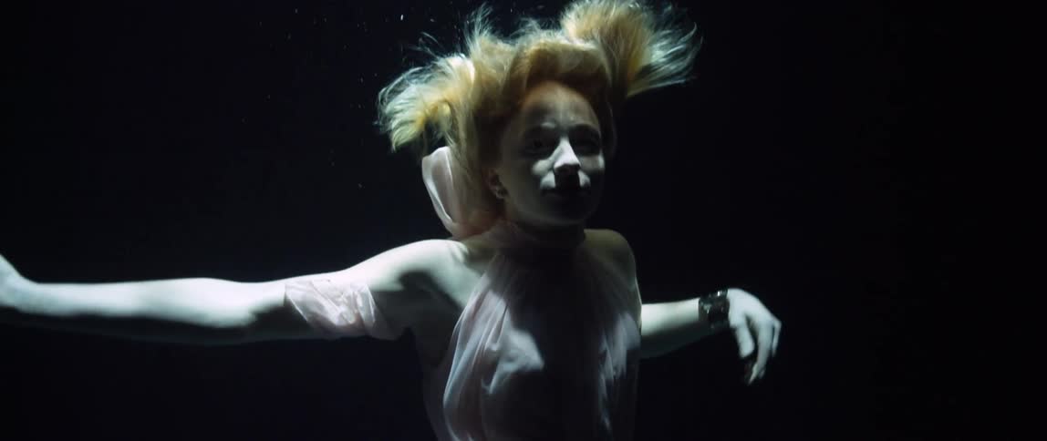 A woman dancing underwater while continuing to sink
